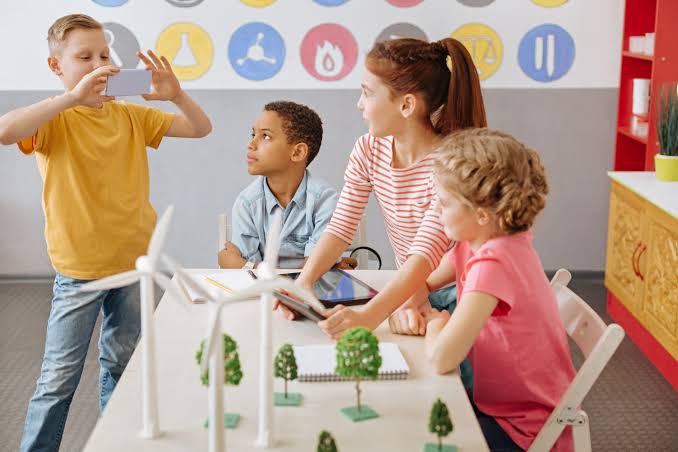 Four children working together at a table on a model wind farm.